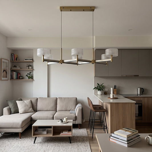 A statement 6-arm crossed pendant chandelier in brushed brass with dark accent arms, topped with six drum shades of clear textured glass.
