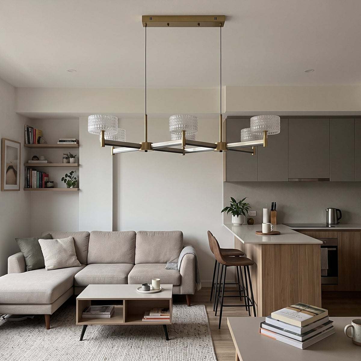 A statement 6-arm crossed pendant chandelier in brushed brass with dark accent arms, topped with six drum shades of clear textured glass.