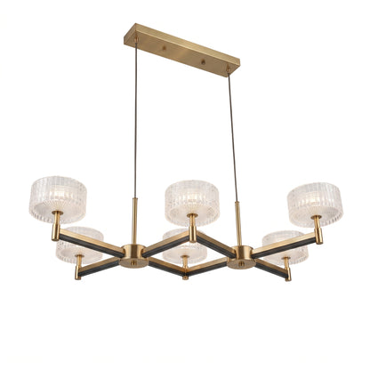 A statement 6-arm crossed pendant chandelier in brushed brass with dark accent arms, topped with six drum shades of clear textured glass