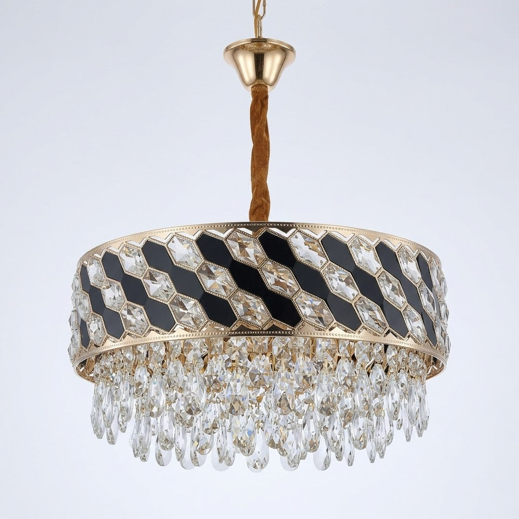 Gold-finished circular chandelier with black inlay panels and hanging crystal prisms, shown on a white background.