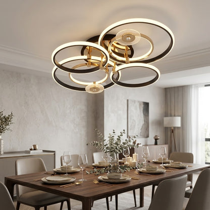 Luxury LED ceiling light with black and gold rings installed above a dining table.