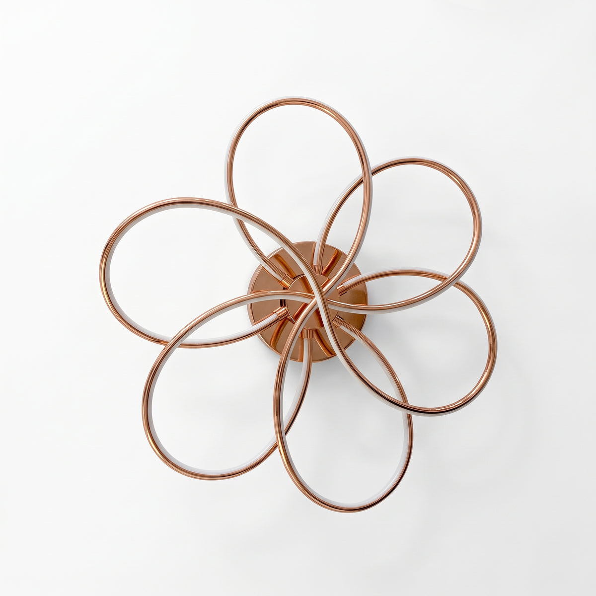 A modern LED ceiling light shaped like a flower, with six sweeping loops in a polished rose gold finish