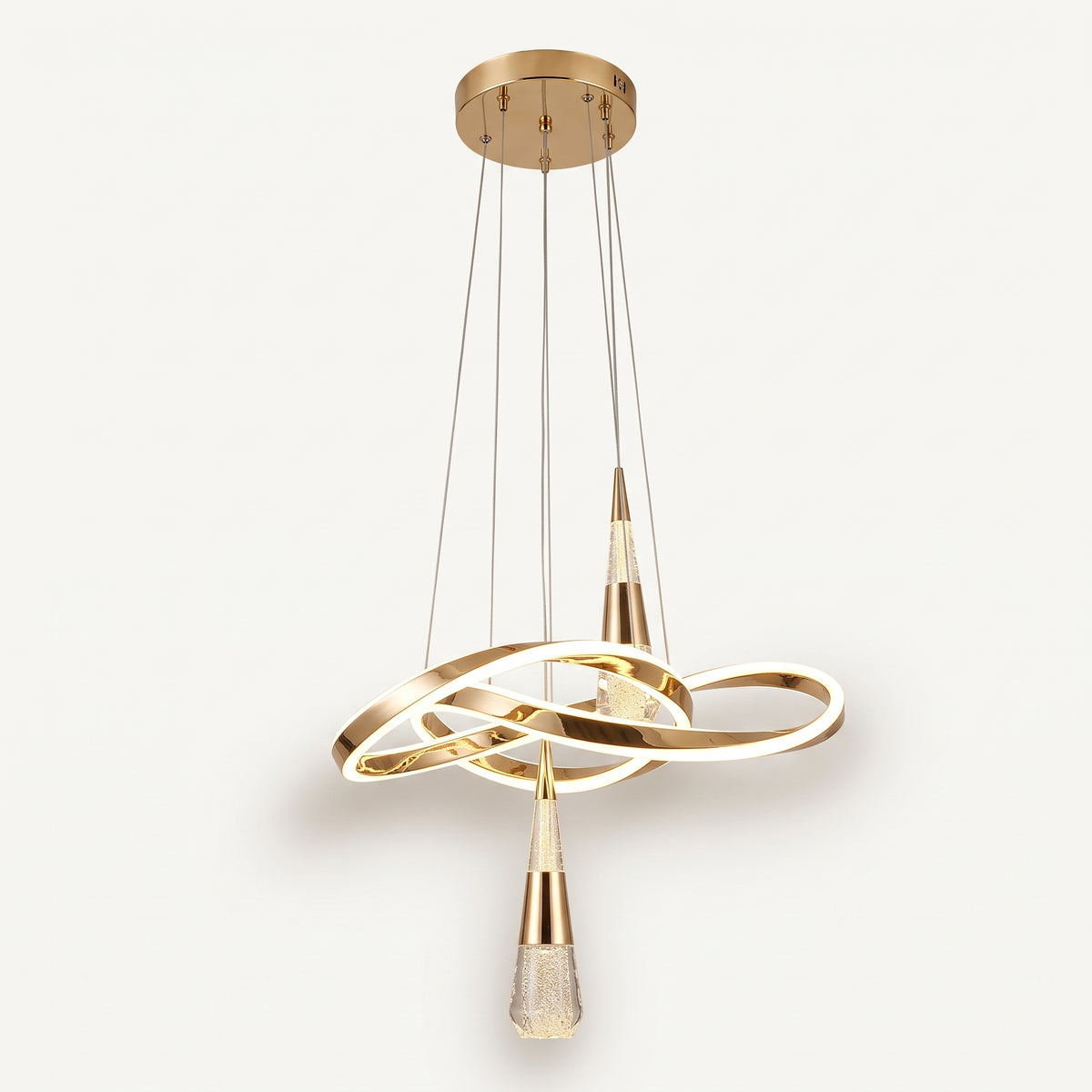 A modern pendant light with a sculptural, flowing gold LED ribbon that loops and twists, with two crystal-bubble teardrop pendants hanging from it. 