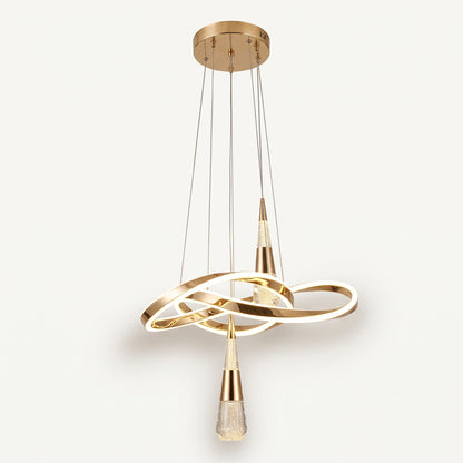 A modern pendant light with a sculptural, flowing gold LED ribbon that loops and twists, with two crystal-bubble teardrop pendants hanging from it. 