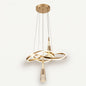 A modern pendant light with a sculptural, flowing gold LED ribbon that loops and twists, with two crystal-bubble teardrop pendants hanging from it. 