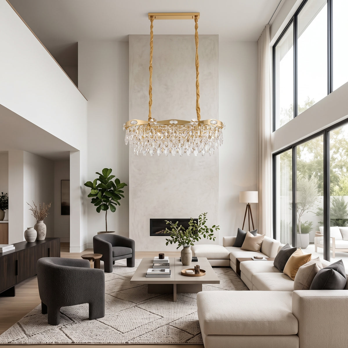 Gold linear crystal chandelier in a high-ceilinged modern living room with a beige sectional sofa and dark grey armchairs