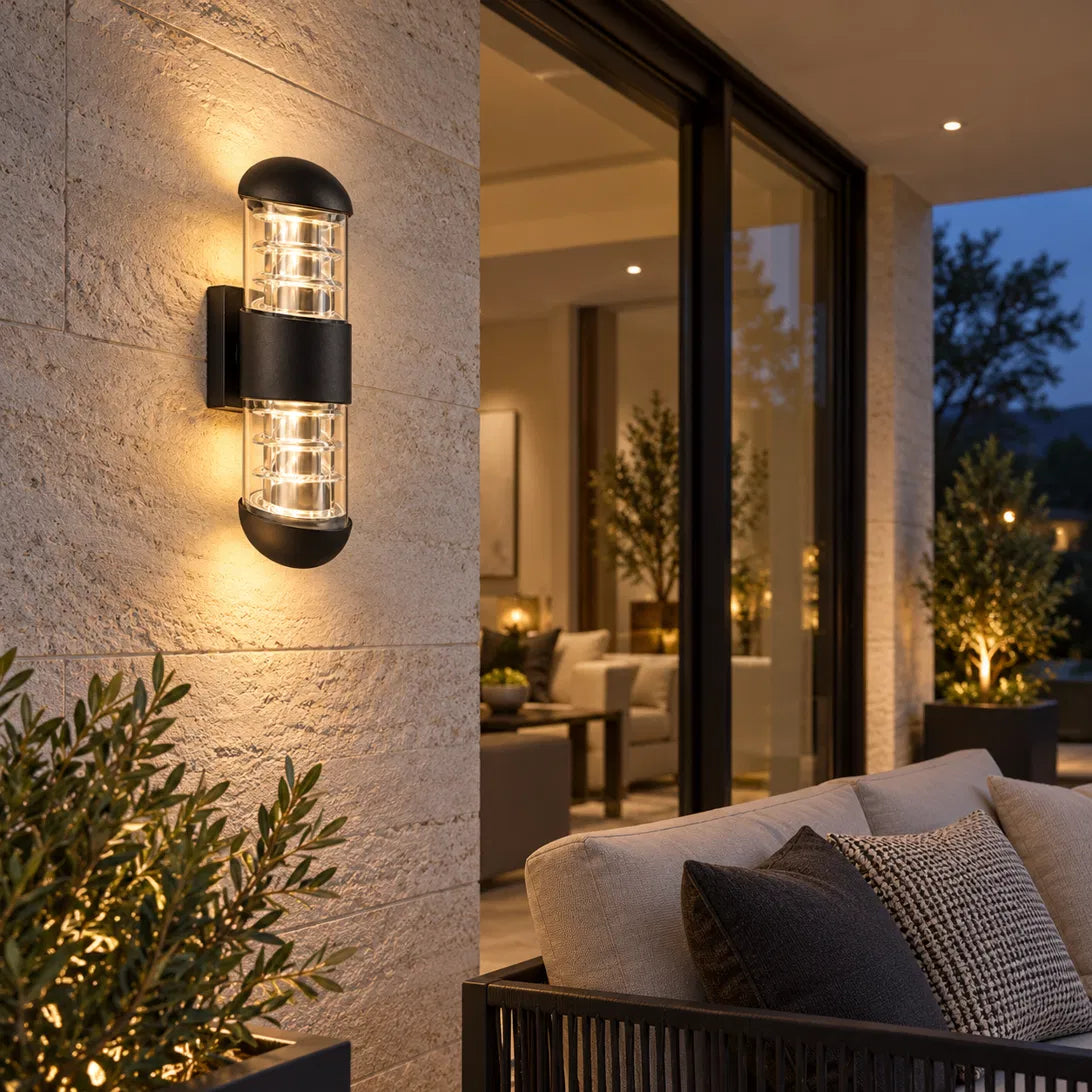 A Sunrise Lion rounded outdoor wall lantern in black aluminium and glass, with a domed cap and a ribbed cage design that casts a warm, decorative glow on the wall.